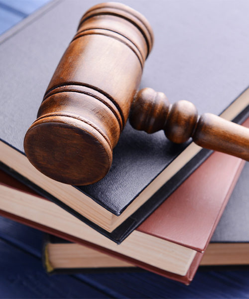 A photograph of a gavel resting atop three stacked books, each placed on another.